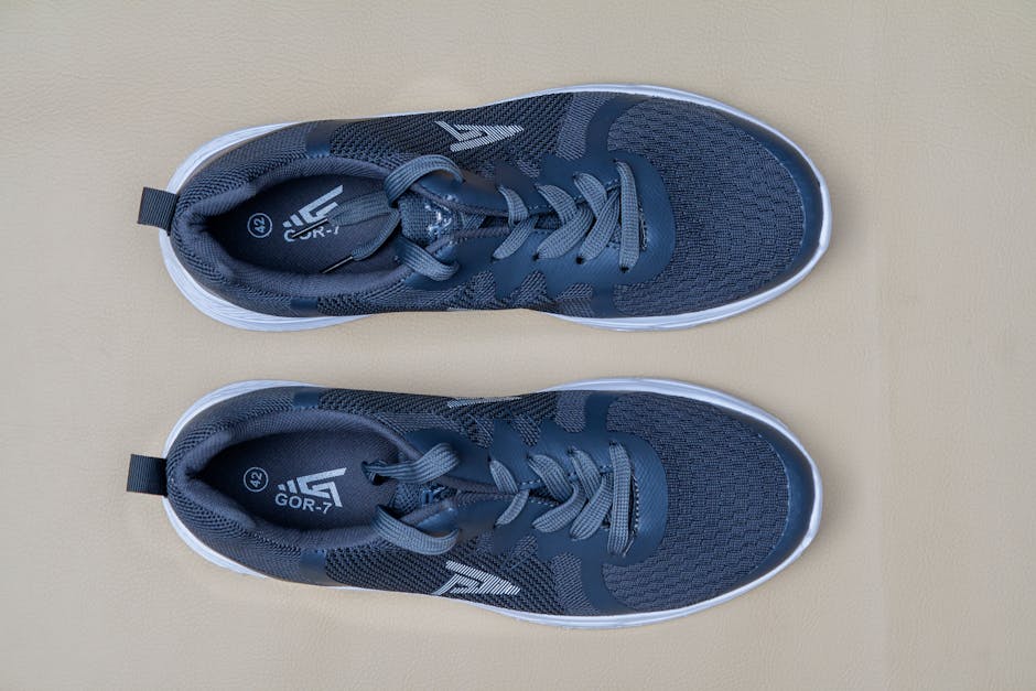 Pair of blue sports trainers captured in a top view on a beige surface, ideal for fitness themes.