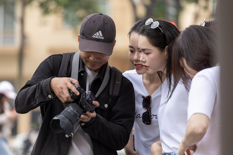 A group of young adults in Hanoi reviewing photos on a camera screen. Outdoor urban setting.