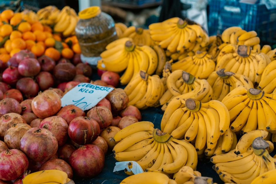 Vibrant stall with bananas, pomegranates, and oranges on display at a market.