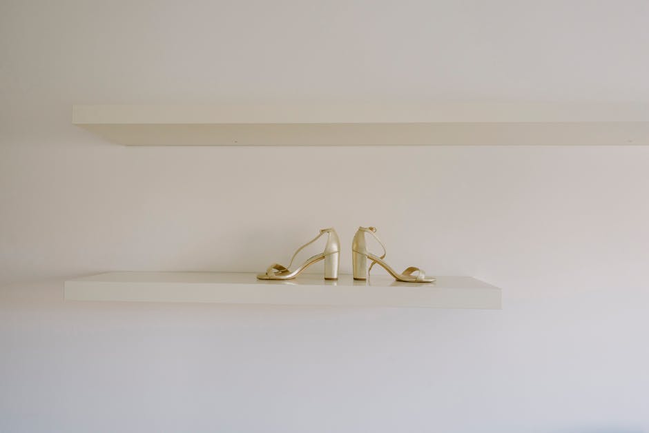 Stylish gold heels elegantly displayed on a minimalist shelf, perfect for fashion and retail themes.