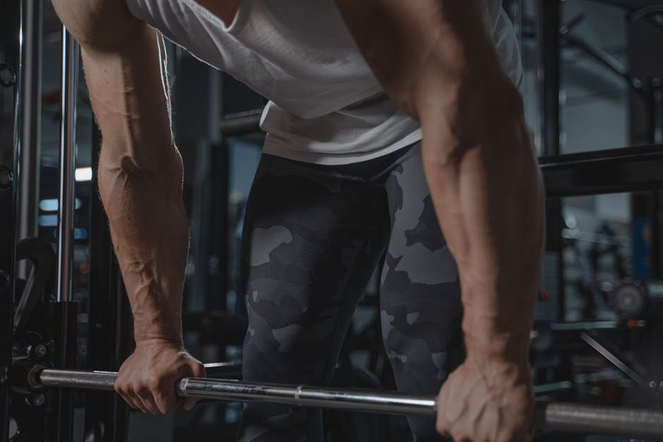 Close-up of a muscular man lifting a barbell indoors, highlighting strength and fitness.