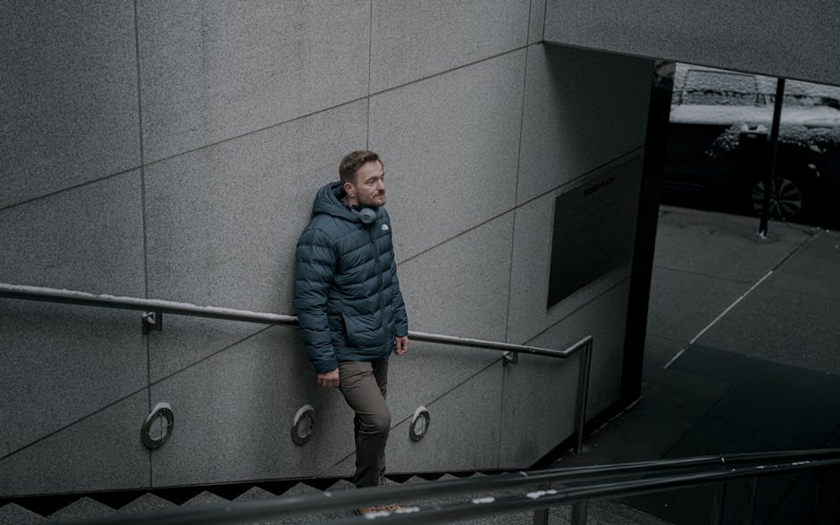 Casual man in a blue jacket stands on an outdoor stairway in New York City.
