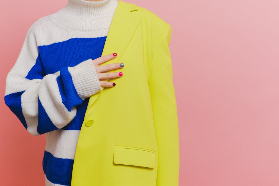 Close-up of a colorful outfit showing a knitted sweater with a yellow blazer and vibrant nails.