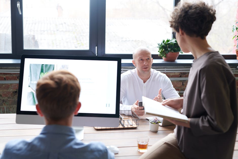 Three colleagues engage in a productive team meeting in a bright, modern office space.