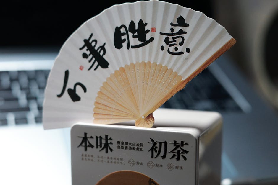 Close-up of a beautiful Asian paper fan featuring calligraphy, highlighting cultural elegance.