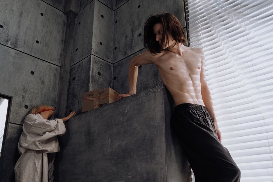 A contemporary scene with two individuals in a dramatic, industrial-style loft.
