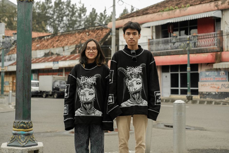 Fashionable young couple in matching streetwear standing on an urban sidewalk.