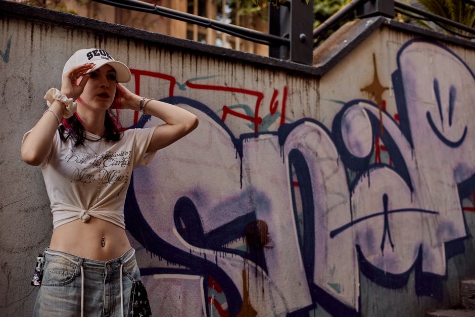 Stylish woman poses confidently in front of vibrant graffiti in Istanbul, showcasing urban fashion.