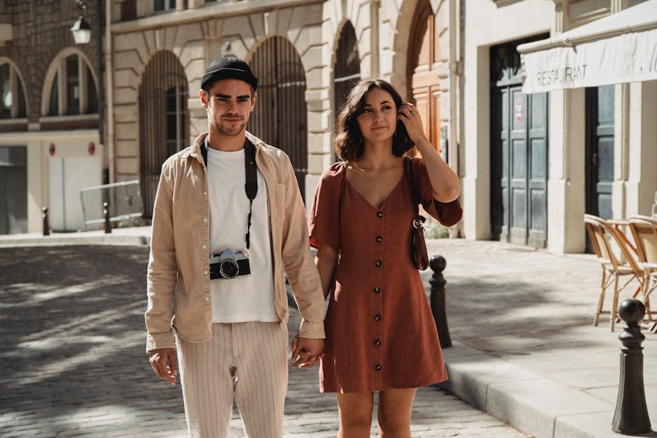 A fashionable couple enjoys a sunny walk on a charming European-style street.