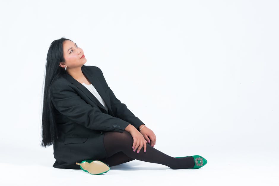 A woman in a business suit sits confidently on a white background, showcasing her professional demeanor.