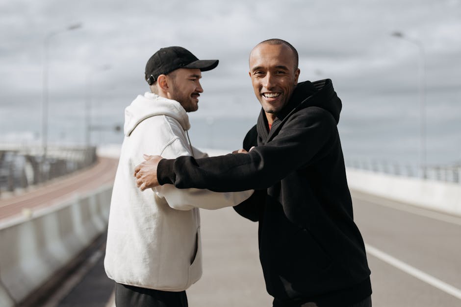 Two friends smiling and embracing on a sunny day outdoors on a road.