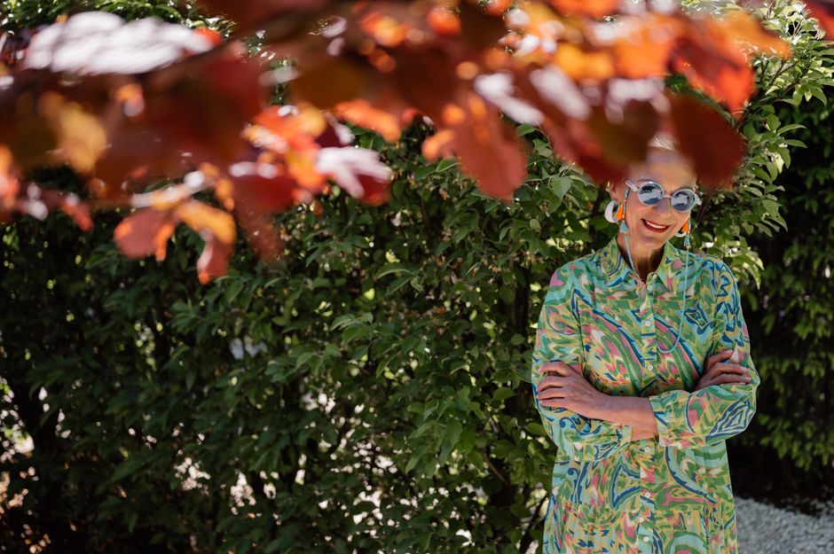 Elegant senior woman in colorful dress with sunglasses, enjoying a sunny day outdoors.