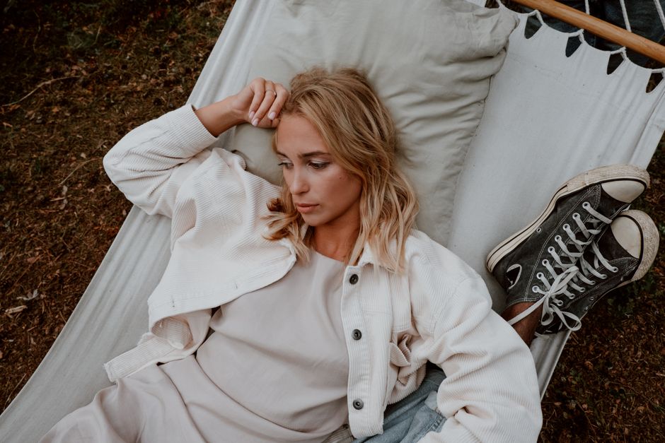 A thoughtful woman lying in a hammock outdoors, exuding calm and introspection.