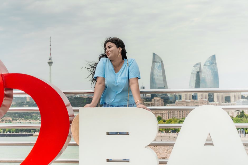 Portrait of a woman in Baku with the Flame Towers and Baku TV Tower in the background.