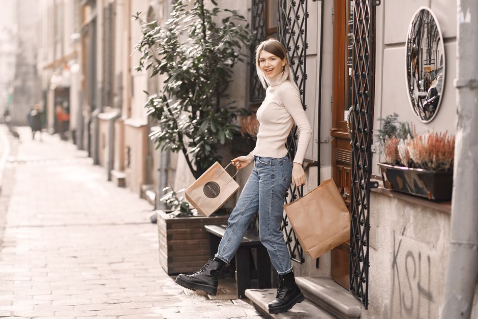 Happy woman with shopping bags on a stylish city street, embracing a joyful shopping experience.