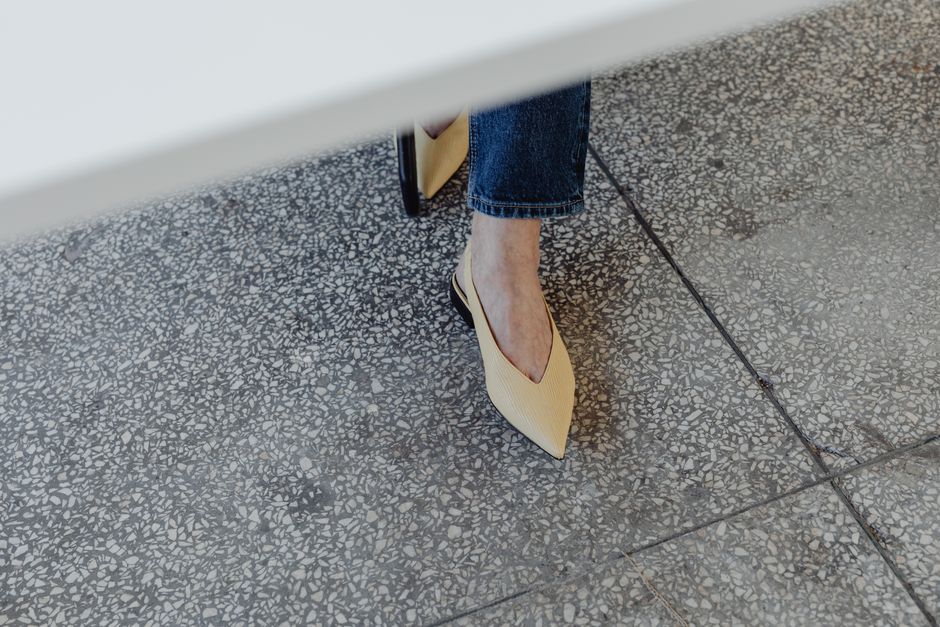 High angle shot of elegant yellow shoes on a textured floor.