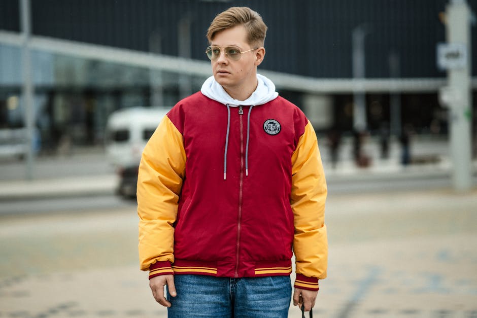 Man wearing a fashionable red and yellow jacket on city streets, highlighting modern urban style.