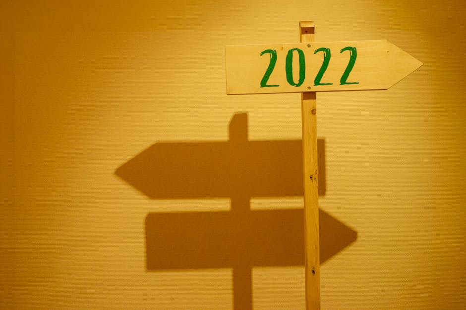 Wooden signpost displaying '2022' with shadow cast on a wall in warm lighting.