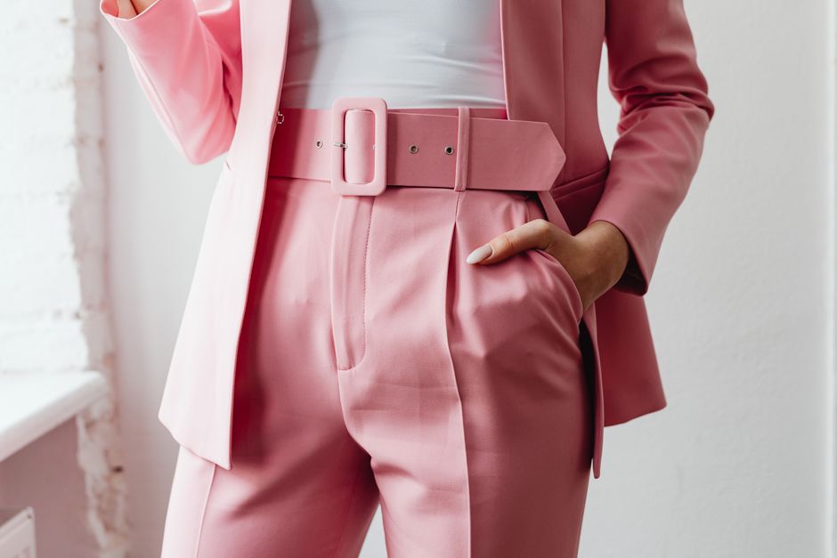 Woman in a pink suit with a wide belt, hand in her pocket